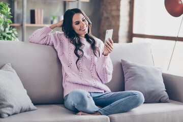 Obraz premium Full size photo of charming attractive young woman sit couch look phone good mood indoors inside house