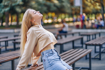 Young woman on a park bench with long blond hair.