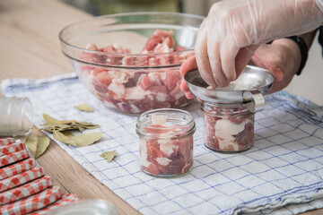 Frau füllt Schulter Fleisch roh mit Trichter und Einweg Handschuhen hygienisch in Schraubglas mit...