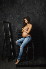 Obraz na płótnie Canvas Portrait of young pregnant woman wearing jeans with beautiful long hair