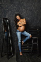 Portrait of young pregnant woman wearing jeans with beautiful long hair