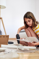 Little girl assembling furniture in a new home - moving into a new home concept.