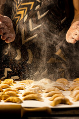 Strong men's hands sprinkle flour dumplings. Ukrainian national dish.