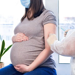 Doctor giving COVID-19 coronavirus vaccine injection to pregnant woman. Vaccination Young Pregnant...