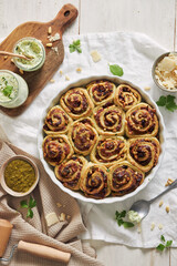 Vertical shot of pesto pizza rolls with pine nuts and herbs butter on a white table