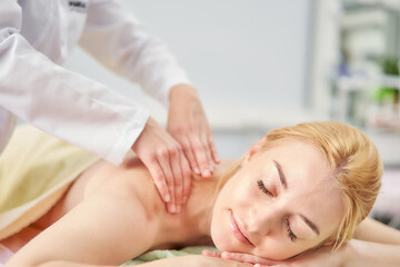 Obraz na płótnie Canvas Women's hands of a specialist massage the woman's back. Therapeutic massage for spinal scoliosis.