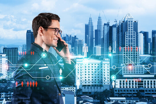 A young handsome eastern businessman processing conference call to develop social media marketing strategy to achieve business goals. Hologram icons over Kuala Lumpur background. - Powered by Adobe