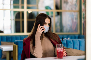 Close up portrait of a caucasian female wearing a medical mask and standing in the street and cafe