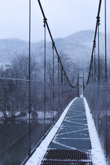 Hanging bridge over the river.Mountains in background.Winter image.