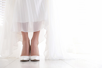 Young bride wearing beautiful wedding shoes indoors, closeup. Space for text