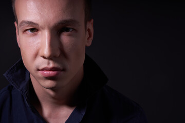 Close up portrait of a beautiful confident young man on a black isolated background in a Studio with copy space, he looks at the camera