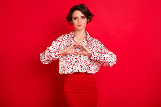 Photo portrait of girl making heart shape with hands isolated on bright red colored background
