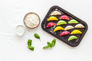 Top view of colorful raw dumplings on baking sheet