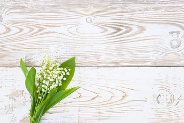 Fototapete Happy spring holiday greeting card. Bouquet of lilies of the valley on rustic white paint wooden background. Space for text, flat lay © stsvirkun