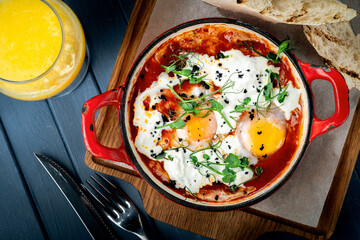 Shakshuka is a traditional Israeli egg dish with tomato sauce and vegetables in a frying pan close up