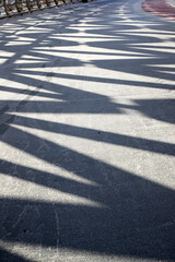 Fototapeta premium vertical view of geometric shadows of a metal frame on icy pathway of pedestrian bridge