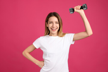 Woman with dumbbell as symbol of girl power on pink background. 8 March concept
