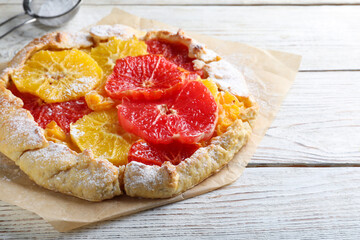 Delicious galette with citrus fruits on white wooden table, closeup