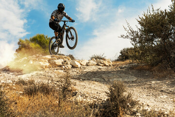 Professional bike rider jumping during downhill ride on his bicycle