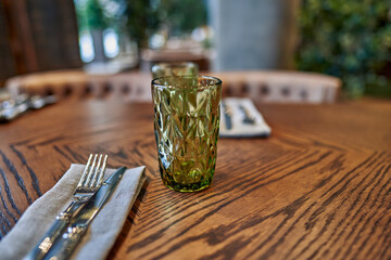 Close-up of cutlery and a glass of Bohemian glass on the table top in an elite restaurant.