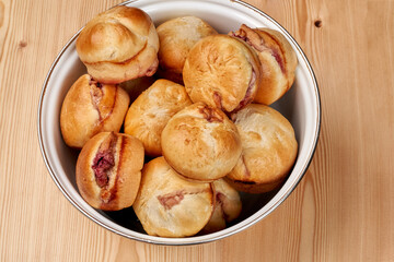 Fresh homemade baked goods. A bunch of cherry buns lie on a plate. Close-up.