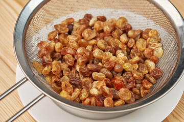 Close up of a bunch of raisins in a colander. Natural organic addition to the dough.