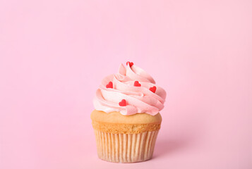 Tasty cupcake with heart shaped sprinkles for Valentine's Day on pink background