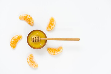 honey in a wooden bowl and orange on a white background