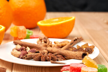 Side view. Still life of orange, candied fruits, nuts, cinnamon sticks, raisins on a wooden background. Close-up.