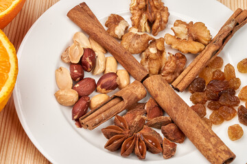 Still life. On a white plate, close-up of nuts, raisins, cinnamon, star anise.