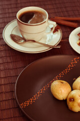 Still life - a hot cup of black coffee, homemade cookies with fruit, baked apples on a bamboo mat
