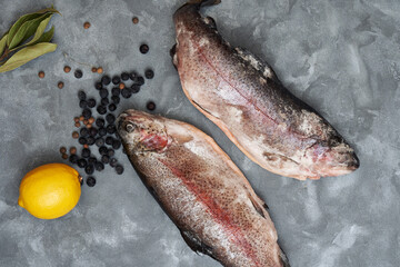 Fresh frozen arctic fish salvelinus alpinus, salmon family, with lemon, pepper and berries on the table, close-up. Delicious freshwater fish from the stream, trout with omega for diet food.