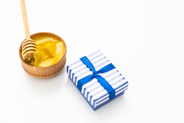 honey in wooden bowl and gift on white background