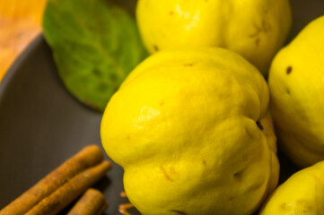 large yellow quince fruits on a ceramic plate, with anise, cinnamon, and walnuts