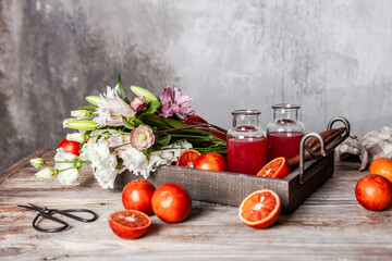 fresh blood orange juice in glasses and in bottle with fresh oranges in wooden tray on wooden table, copy space