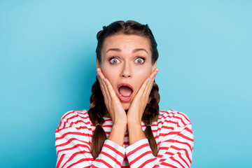 Photo of young girl amazed shocked surprised news fake novelty hands touch cheeks isolated over blue color background