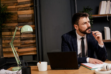 Young businessman using laptop in his office. Businessman taking a notes while working on laptop.