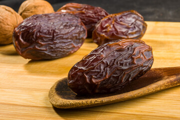 Big luxury dried date fruit on the wooden board, kurma ramadan kareem concept, close up.