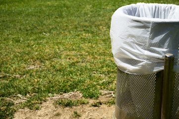 Fototapeta premium Trash bin in a park with white plastic bag
