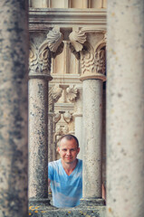 Young man traveler looking at camera and posing between stone columns of medieval Leiria castle in Portugal on vacation, vertical view