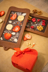 Handmade chocolate with fresh and dried fruits on light paper background in rustic style