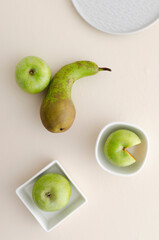 Top view of plate, bowls and fresh juicy aplles and pear on the bright table