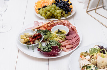 Food tray with delicious salami, pieces of sliced ham, sausage. Cutting sausage and cured meat on a celebratory table.