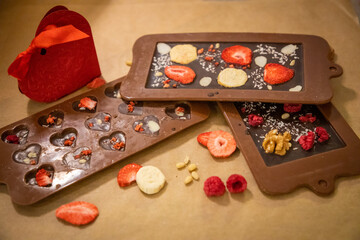 Handmade chocolate with fresh and dried fruits on light paper background in rustic style