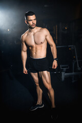Fototapeta na wymiar Muscular athlete posing in a dark gym, portrait of a sporty man