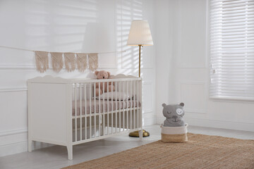 Cute baby room interior with comfortable crib and teddy bear