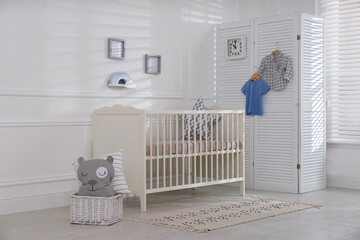 Cute baby room interior with comfortable crib and clock