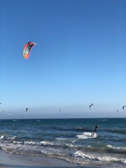 Gente practicando kitesurf en el mar lleno de cometa de colores