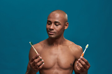 Fototapeta premium Afro-American man watching positively the eco friendly toothbrush