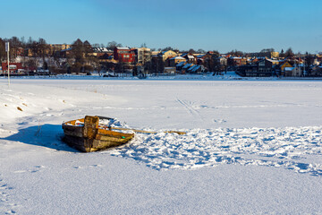 Wooden old boat in a frozen river or lake in a evening winter.